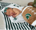 Baby laying on Michigan State University four layer muslin blanket - soft green and white Spartans baby blanket for tummy time and play"